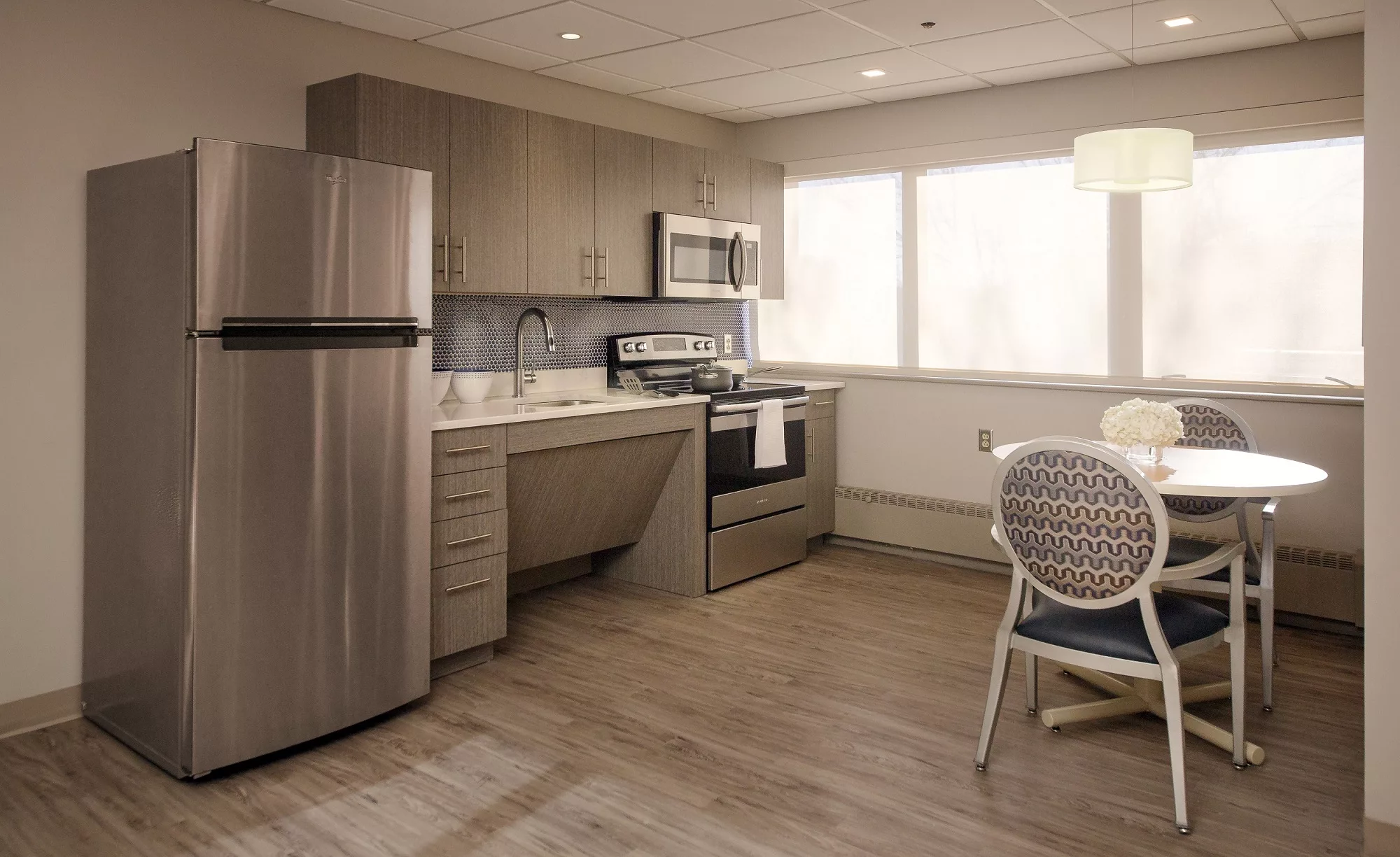 A modern kitchen with stainless steel appliances and a small dining area.