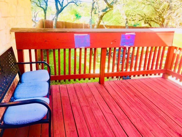 A bright outdoor deck with a chair and wooden railing on a sunny day.