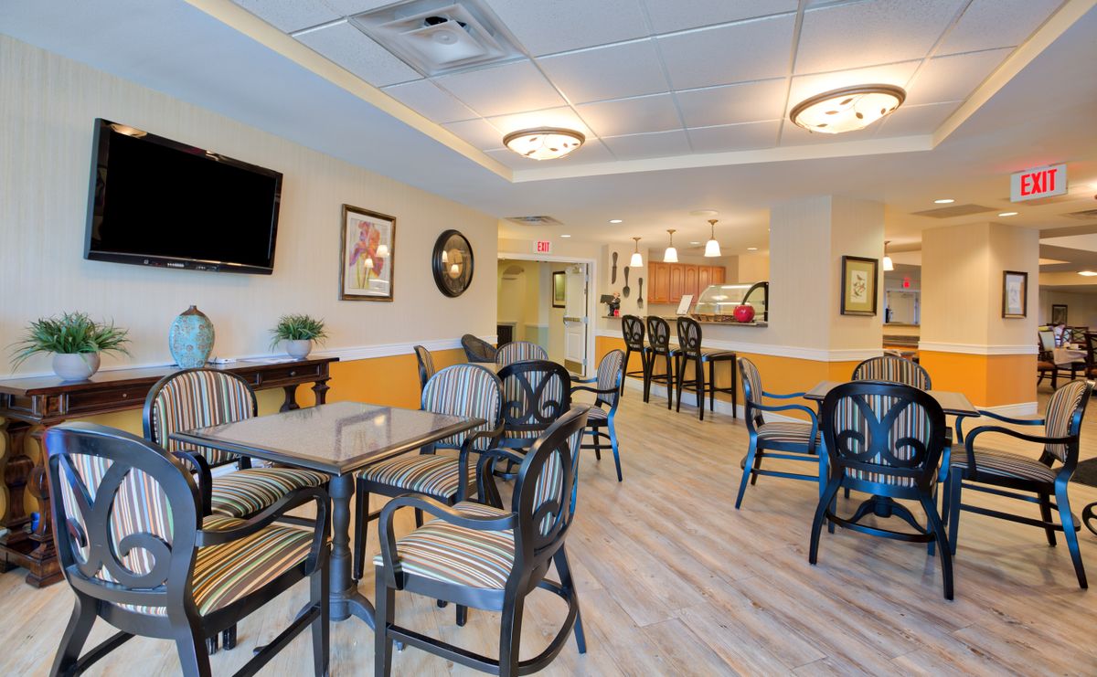 A cozy dining area with tables, chairs, a bar counter, and a wall-mounted television.