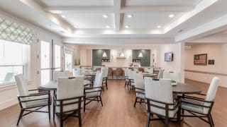 A modern dining area with neatly arranged tables and chairs, featuring elegant lighting.