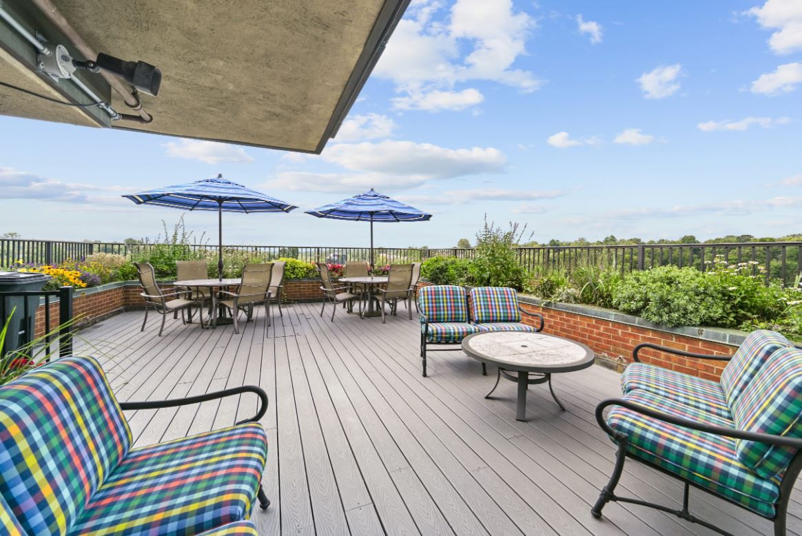 A spacious outdoor patio with comfortable seating and umbrellas under a partly cloudy sky.