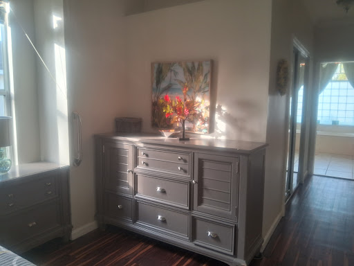 A stylish dresser in a well-lit hallway, adorned with decorative elements and a vibrant piece of wall art.