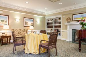 A cozy living room setting with a round table, two chairs, a bookshelf, and a fireplace.