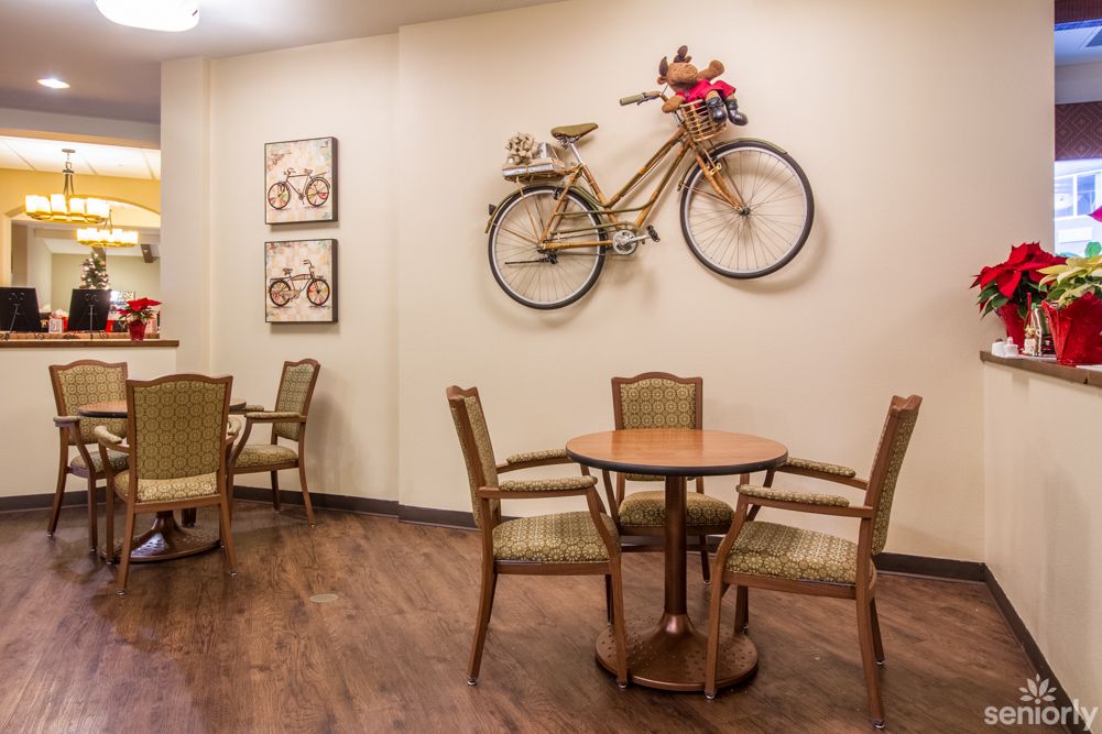 A cozy cafe interior featuring a bicycle mounted on the wall as decoration, accompanied by tables and chairs on a wooden floor.