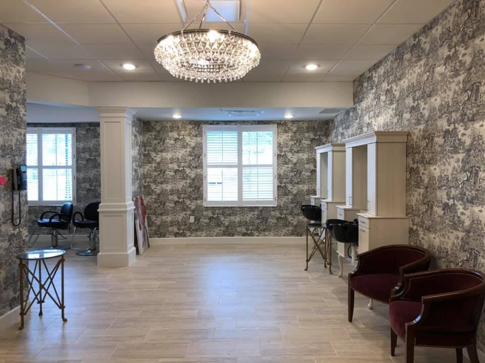 A luxurious salon interior featuring hair stations and a sparkling chandelier.