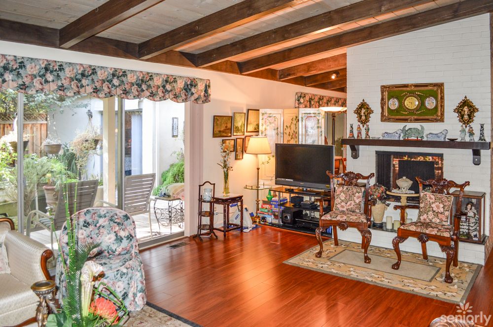 A cozy living room with exposed wooden beams and a stylish interior featuring a television, fireplace, and elegant furniture.