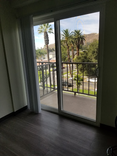 A cozy room with a balcony offering a view of palm trees and greenery.