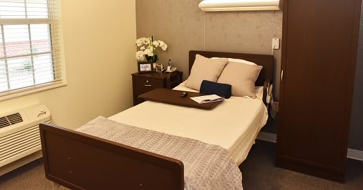 A neatly arranged bedroom with a single bed, nightstand, and decorative flowers.