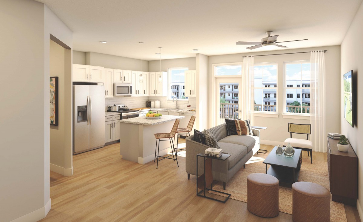 A modern open-concept apartment with a kitchen and living area featuring ample natural light and wood flooring.