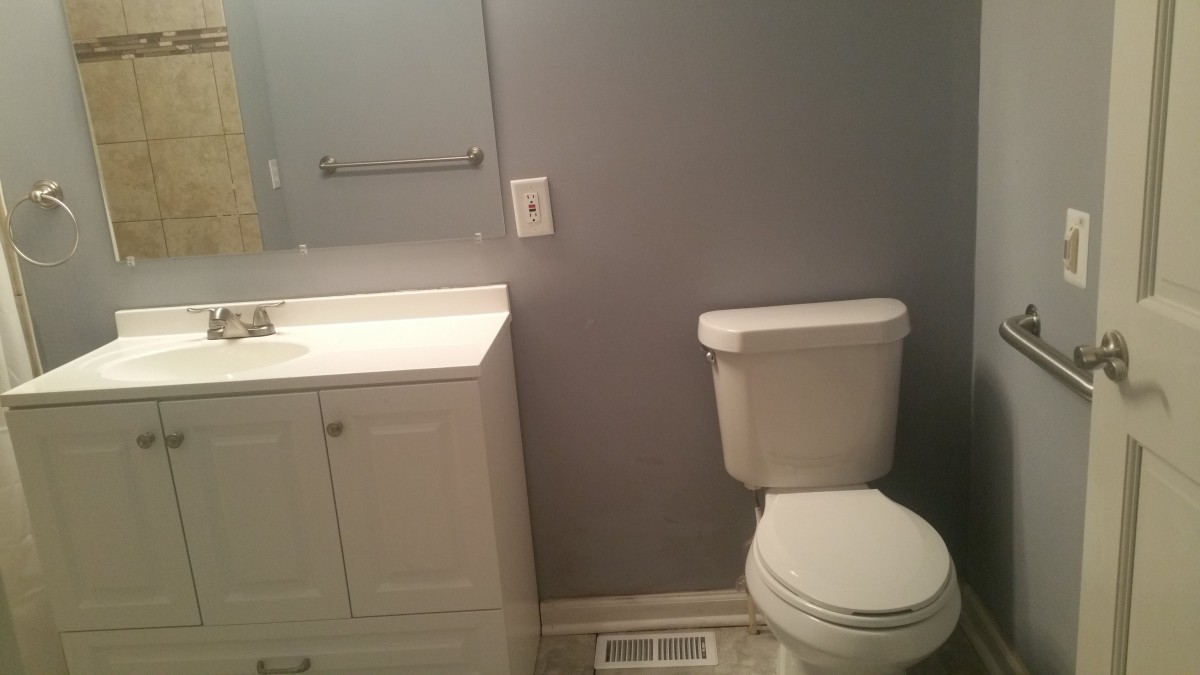 A simple bathroom with a toilet, sink, and cabinet against gray walls.