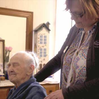 A caregiver providing support to an elderly person in a home setting.