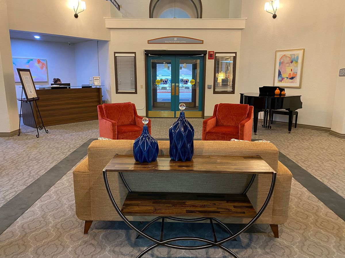 A modern lobby with stylish furniture, featuring red chairs, a sofa, and decorative blue vases on a wooden table.