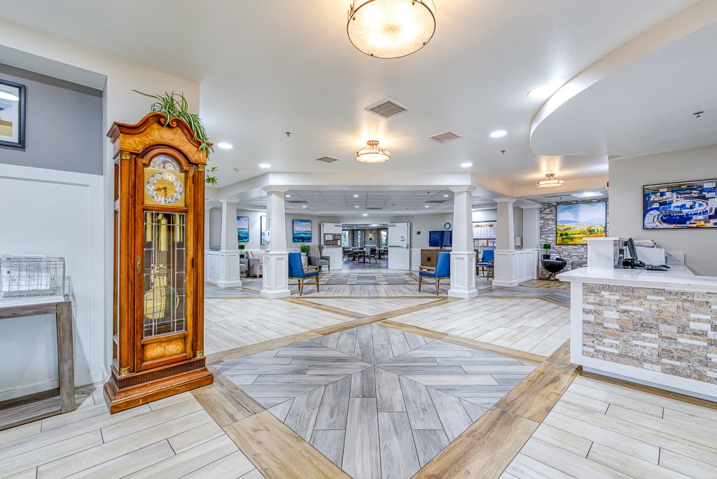 A spacious and modern lobby with a grandfather clock, featuring a white color scheme and elegant floor tiles.