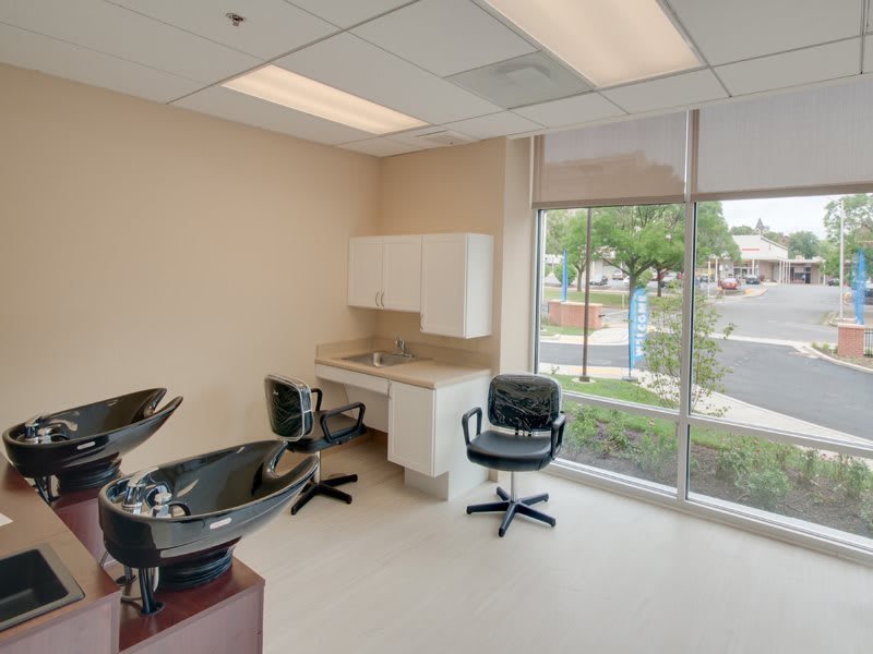 A modern hair salon interior with chairs and sinks near large windows.