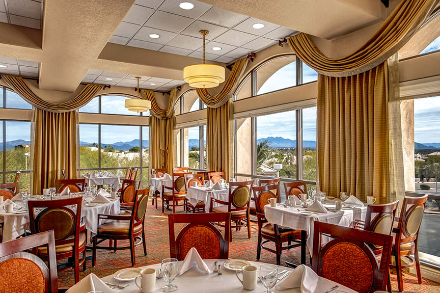 A beautifully set dining room in a restaurant with large windows offering scenic views.