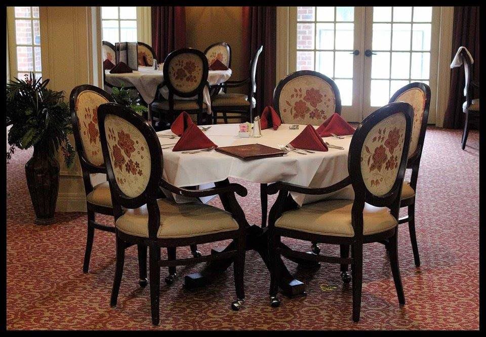 An elegant dining room table set with chairs and neatly folded red napkins.