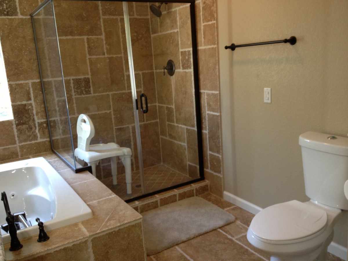 A modern bathroom with a tiled shower, bathtub, and toilet.