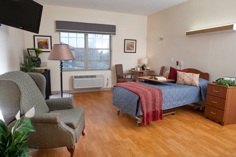 A cozy bedroom featuring a bed, armchair, and window with natural light.
