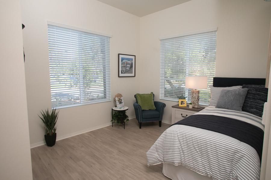 A cozy bedroom with large windows, a comfortable chair, and modern decor.