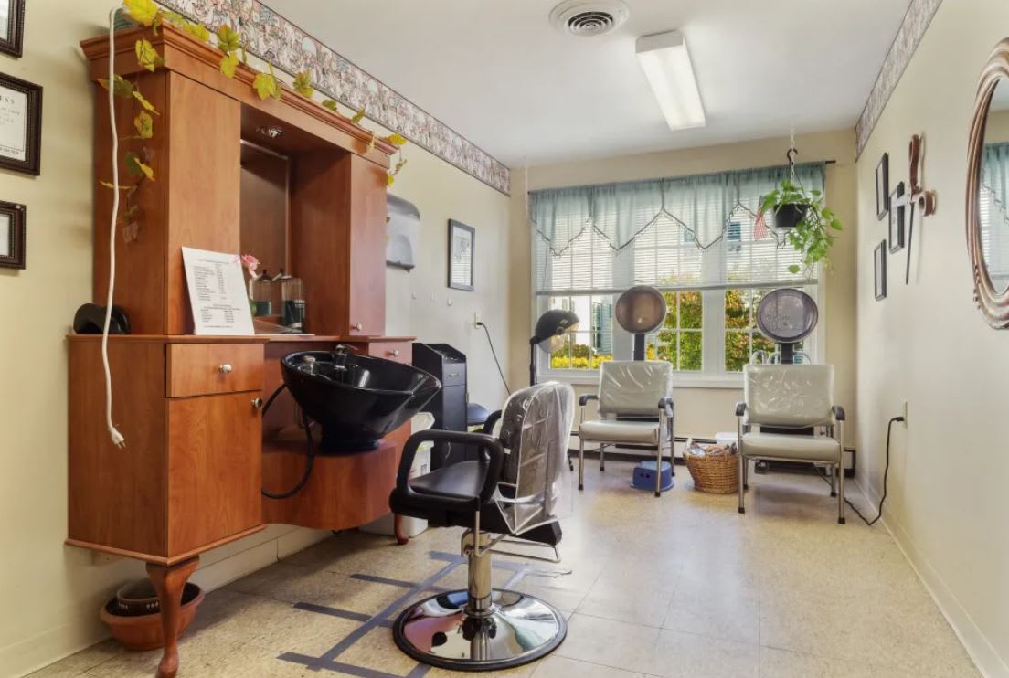 A cozy hair salon interior with styling chairs and hair dryers by the window.