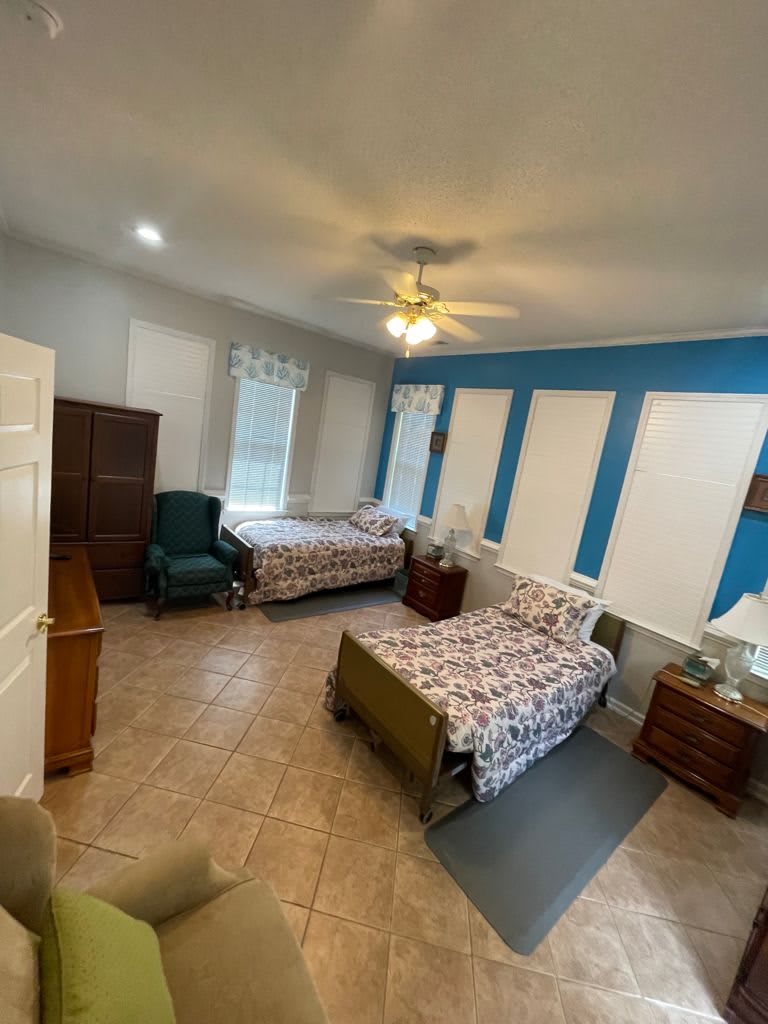 A cozy bedroom with two beds, featuring a blue accent wall and tile flooring.