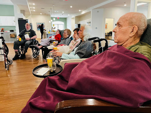 Residents engaging in a social gathering at a care facility, sharing refreshments and conversation.