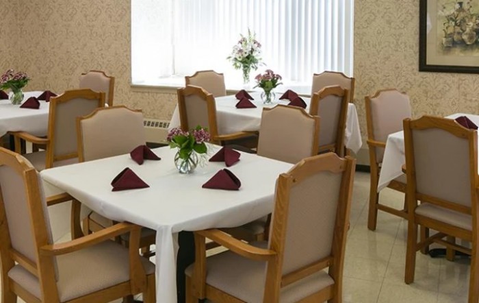 Elegant dining area with neatly arranged tables and chairs, featuring white tablecloths and decorative flowers.