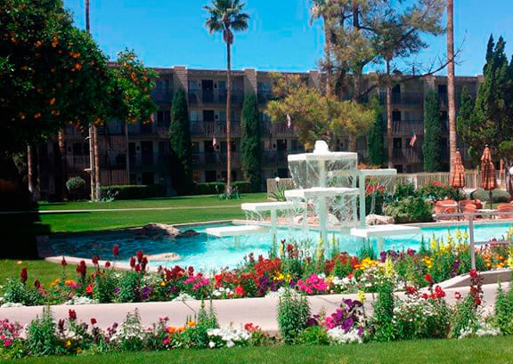 A tranquil garden scene with a central fountain surrounded by colorful flowers and lush greenery.