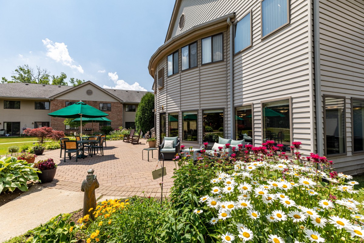 A sunny patio area with outdoor seating and a garden filled with vibrant flowers.