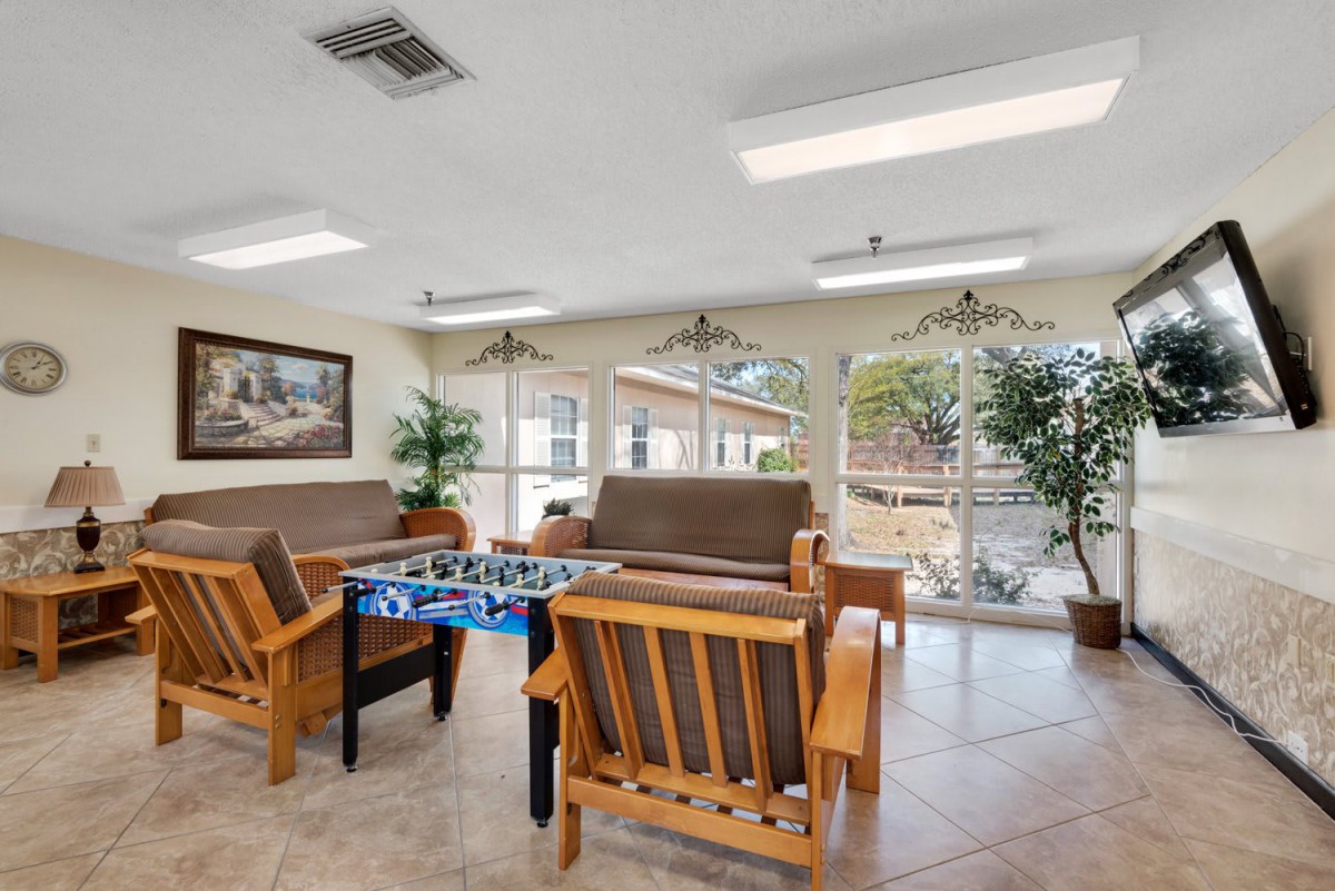 A cozy lounge area with comfortable seating and a foosball table, well-lit by natural light through large windows.