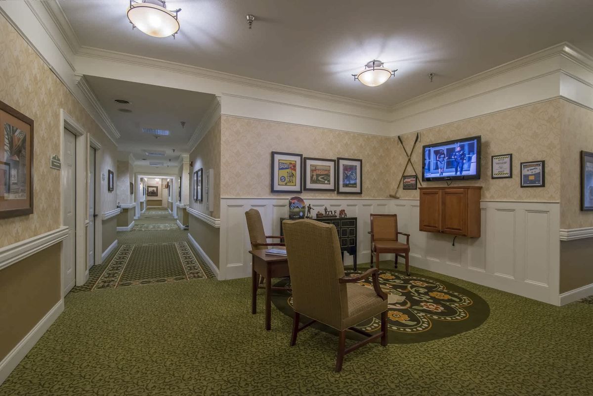 A cozy hallway with seating and decor, featuring a television and framed paintings along the walls.