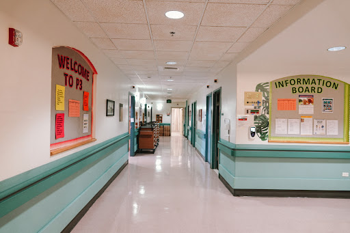 A brightly lit hospital hallway with colorful decorations and welcoming signage.