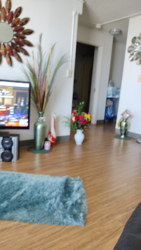 A cozy living room with vibrant flower arrangements and a television, creating a warm atmosphere.
