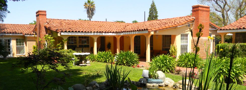 A Spanish-style courtyard with a red tile roof and lush garden.