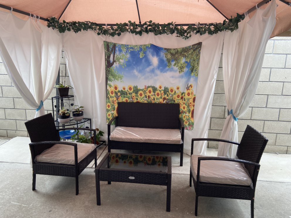 A cozy outdoor patio setup with a canopy, curtains, and comfortable seating.