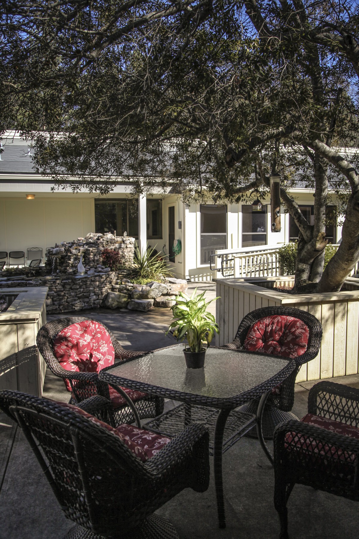 A cozy outdoor patio with a table and chairs surrounded by lush greenery.