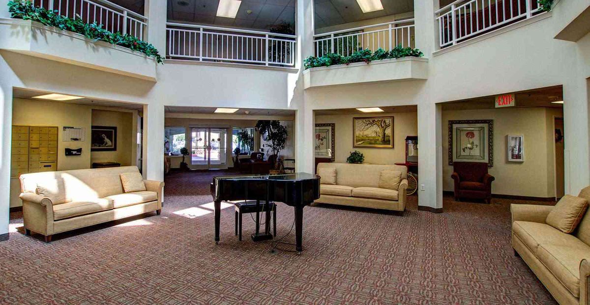 A spacious lobby featuring a grand piano, comfortable sofas, and elegant decor.