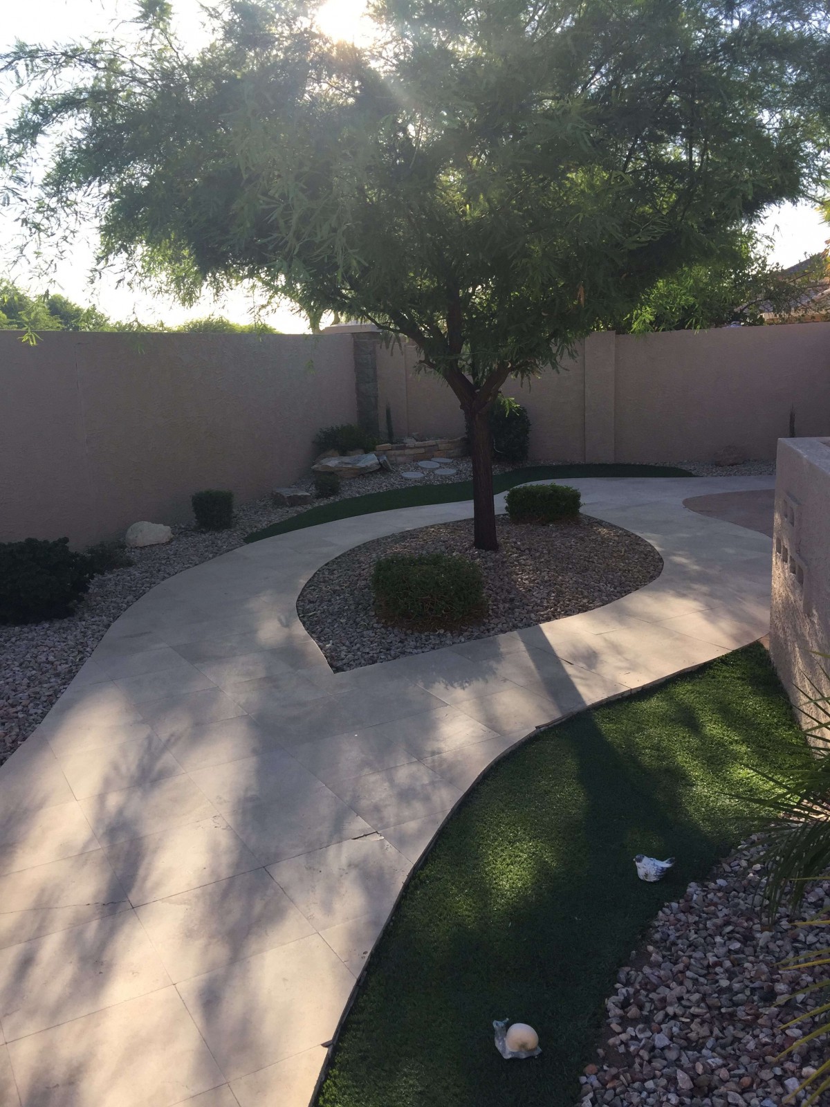 A beautifully landscaped backyard featuring a curved pathway, a large tree, and well-maintained garden areas.
