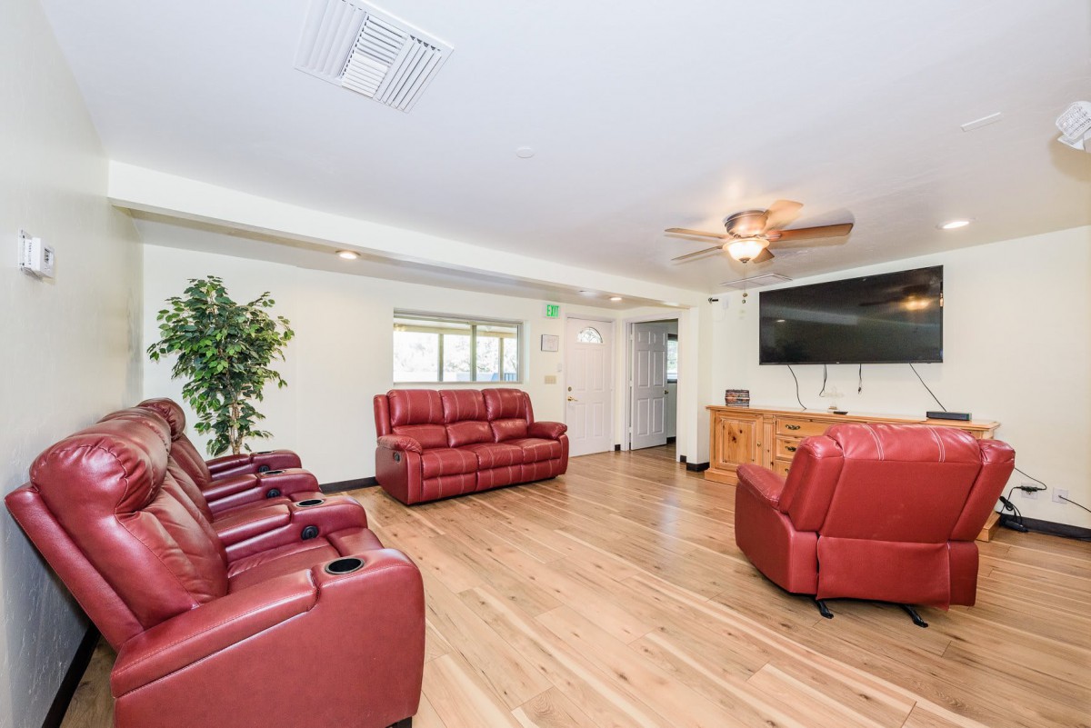 A modern living room with red leather seating and a large flat screen TV.