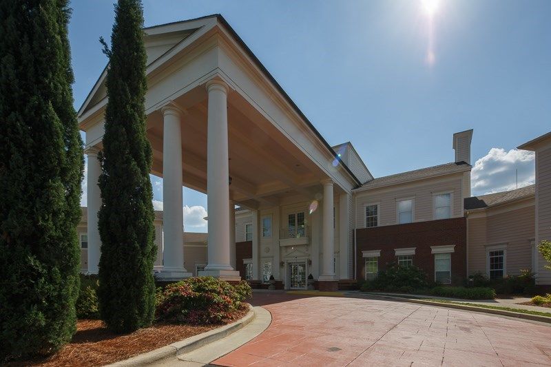 A large building with prominent columns and a covered entrance on a sunny day.
