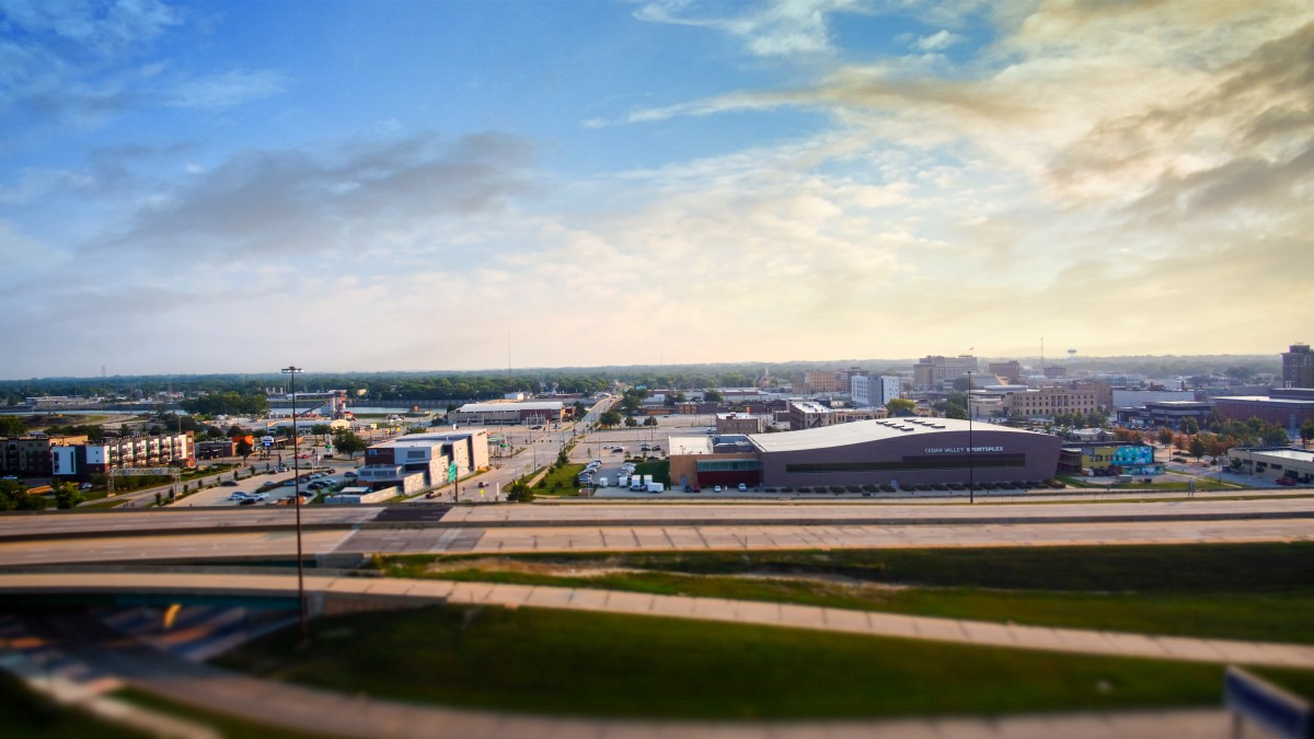 Aerial view of a cityscape with highways and buildings under a colorful sky.