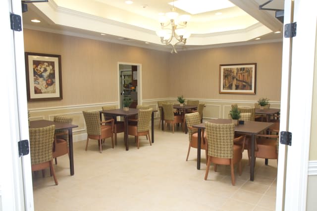 A well-lit dining room with multiple tables and chairs, featuring elegant decor.