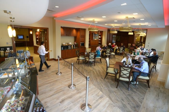 A busy caf with people dining at tables and a server attending to customers.