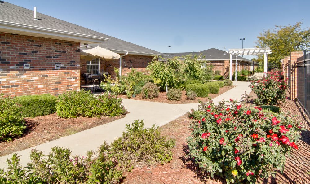 A landscaped garden with pathways and a brick building in the background.