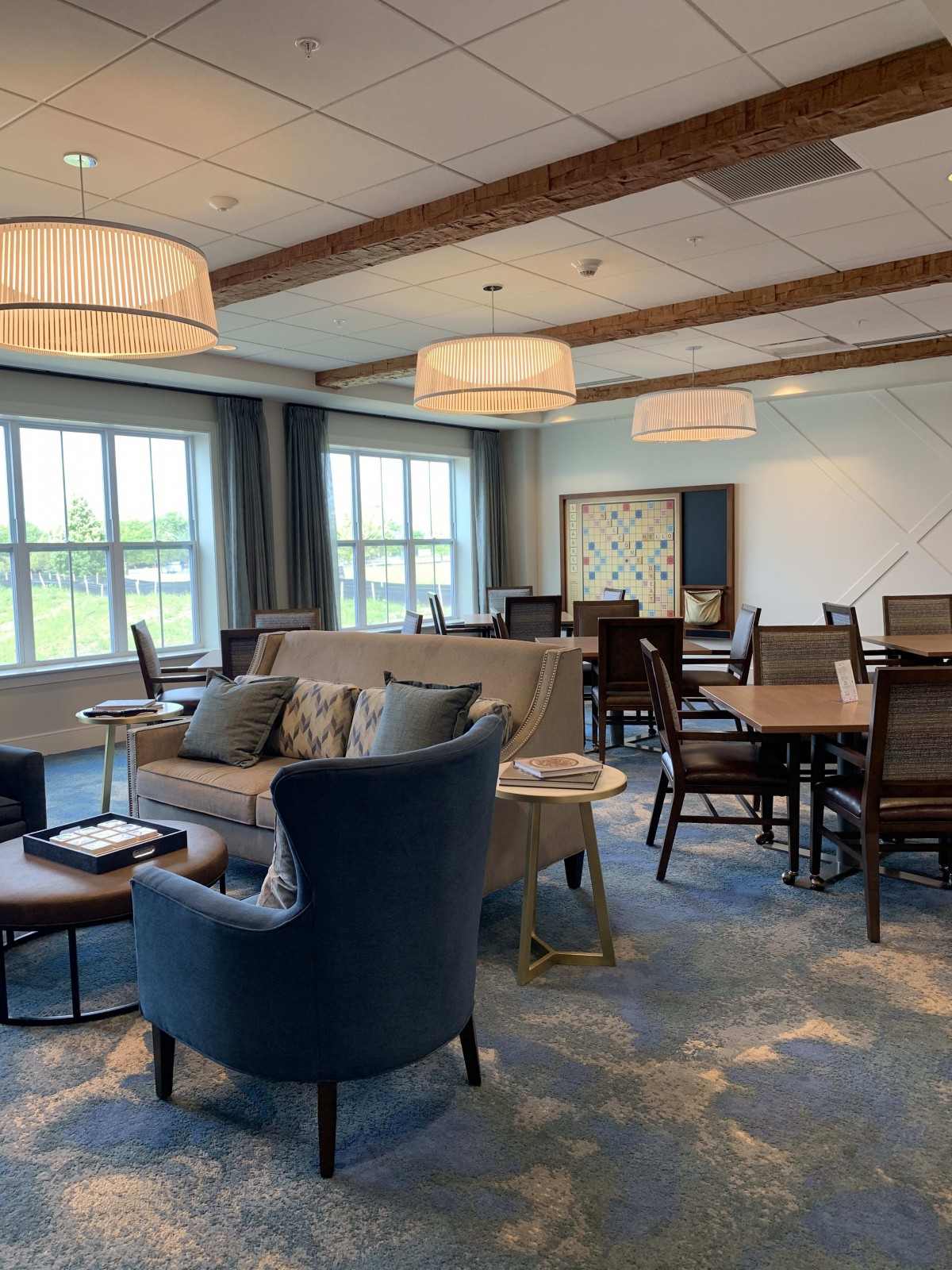 A cozy lounge area with comfortable seating and dining tables, illuminated by large windows and elegant lighting.