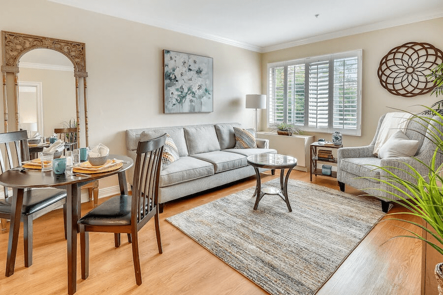 A cozy living room with a sofa, armchair, and coffee table, complemented by a small dining table set.