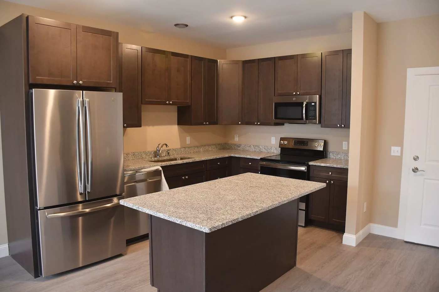 A modern kitchen with dark cabinets, a central island, and stainless steel appliances.