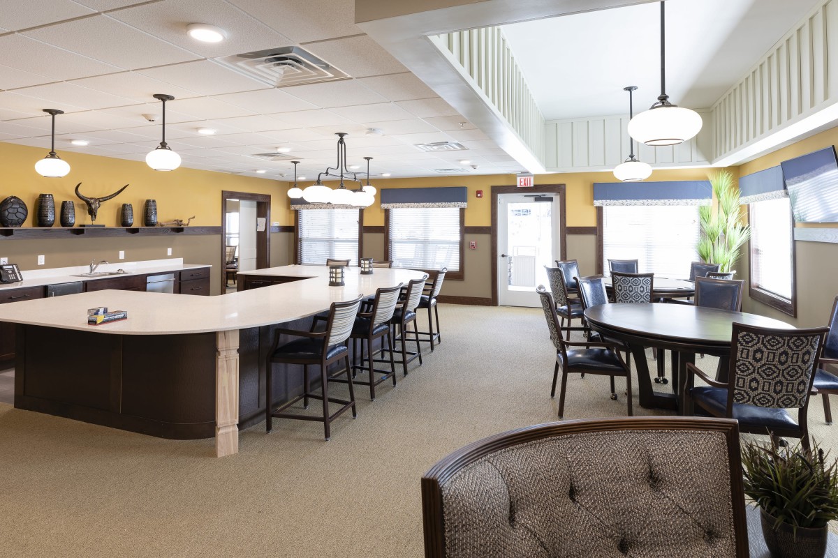 A modern lounge area with seating and dining tables, well-lit by overhead lights.