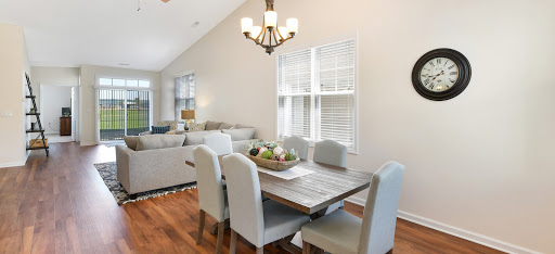 A stylish dining area featuring a wooden table surrounded by gray upholstered chairs, illuminated by a modern chandelier.