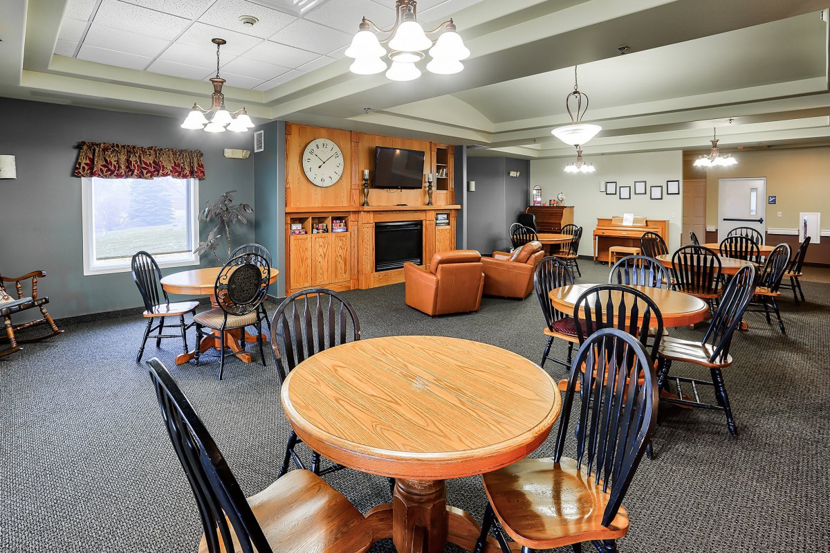 A cozy communal living space featuring wooden tables and chairs, a sofa, and a television set.
